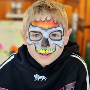 A child with a flaming skull face paint