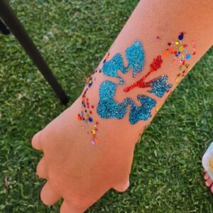 Glitter tattoo of a hibiscus on a child's arm