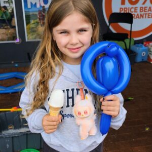 Child holding a balloon twisted to the shape of a parrot on a swing