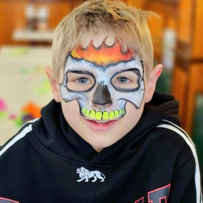 A child with a flaming skull face paint
