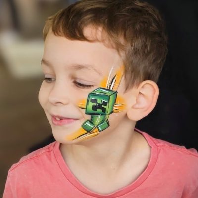 A child with a Minecraft design painted on their face.